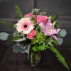 A pretty pink bouquet designed in a clear vase using lilies, Gerbera