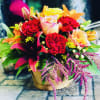 A fresh variety of fall-colored flowers arranged in a reusable basket. 
