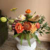 A lush and low arrangement filled with seasonal warmth.  
