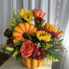 A ceramic pumpkin is filled with a variety of fall flowers. 