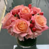 Soft pinky peach roses with rosy accents in a glass vessel
