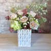 A fun white ceramic modern vase filled with muted lavender/brown roses, mini