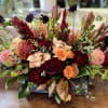 a lush fall arrangement in a wood box. includes orchids, roses, and