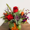 Crimson roses, kale, rust red alstroemeria, purple stock, and millet.