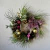An artificial wreath with pink and gold ornaments and a large pink
