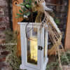 This white wood lantern with tin roof is inserted with a frosted