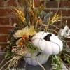 This white ceramic pumpkin is filled with artificial neutral colored flowers and
