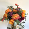 Bright and bold color flower arrangement with autumnal floral and foliage textures.