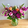 This elegant glass vase is filled with a stunning arrangement of vibrant