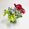Comprised of bright orange red calla lilies, blues thistle and green Anthurium