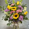 A radiant mix of golden sunflowers, sunny yellow roses, delicate pink spray