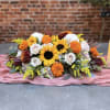 A beautiful, long, and low centerpiece with an abundance of harvest-themed blooms