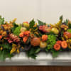A long tray in fall harvest textures including oak leaves, roses, orchid