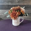 This charming floral arrangement is designed in a keepsake mug and paired