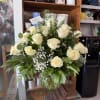 36 white roses in a large glass vase and green foliage