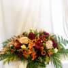 Eye-catching Thanksgiving centerpiece with candles, carnations, alastromeria, mums, and daisies. 
