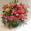 A pastel pink and white arrangement of garden roses, hypericum, greenery, and