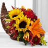 A cornucopia basket filled with fall colors of sunflowers, mum, lilies and