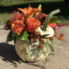 A variety of select fall toned blooms, nestled in a white pumpkin.