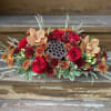 A low and long centerpiece with red roses, butterscotch orchids, white hypericum