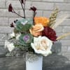 An interesting design with fall colored blooms and greens. Perfect for a
