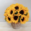 Sunflowers beautifully arranged in a rustic terra cotta pot with seasonal greenery.
