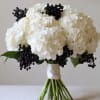 This bouquet of white hydrangea is accented with tinted black berries.