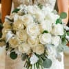 This bridal bouquet features all white roses with a touch of lambs