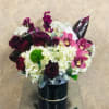 mini calla lilies, burgundy, stock, burgundy roses, orchids, and hydrangeas in a