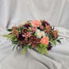 This elegant fall centerpiece features a lush blend of mauve, burgundy, and
