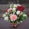 A warm, romantic mix of red roses and soft seasonal flowers, perfect