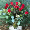 Premium red roses arranged artfully with branches, assorted foliage and unique filler.