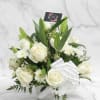 An all-white basket featuring roses, lilies, pom poms, and wax flowers for