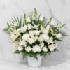 A front-facing arrangement featuring white lilies, roses, snapdragons, chrysanthemums, and carnations. Designed