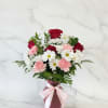 A pink vase arrangement featuring red roses, white daisies, and pink carnations