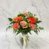 A lively orange and green arrangement featuring roses, daisies, carnations, and button