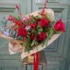 A festive mix of lush evergreens, red proteas, red roses, ilex berries