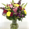 This vase arrangement consists of mixed flowers with bright colors. In the