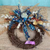 A small wreath with blue and cream colors decorated with pumpkins to