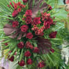 This large funeral tribute features magnificent maroon tropical leaves, fan palm, red
