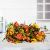 Harvest Glow Centerpiece is a beautiful and festive floral arrangement designed to
