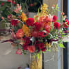 flowers include: freedom roses, free spirit roses, orange orchids, red dahlias, red