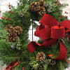 A door wreath with traditional decorations of a red velvet bow, pine