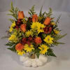 A vibrant fall arrangement of golds and oranges in an elegant white