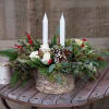 A rich mixture of texture and greens adorned with candles and cones.