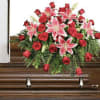 A floral casket arrangement featuring red roses and pink lilies that are