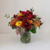 Autumn flowers in a short, glass cylinder vase.  Flowers included selection