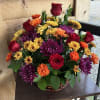 Fall colored flowers neatly arranged in a basket.