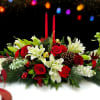 Celebrate the tradition with this elegant centerpiece, composed of roses, lilies, pine