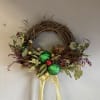 A beautiful, holiday themed small wreath decorated with ornaments and dried flowers.